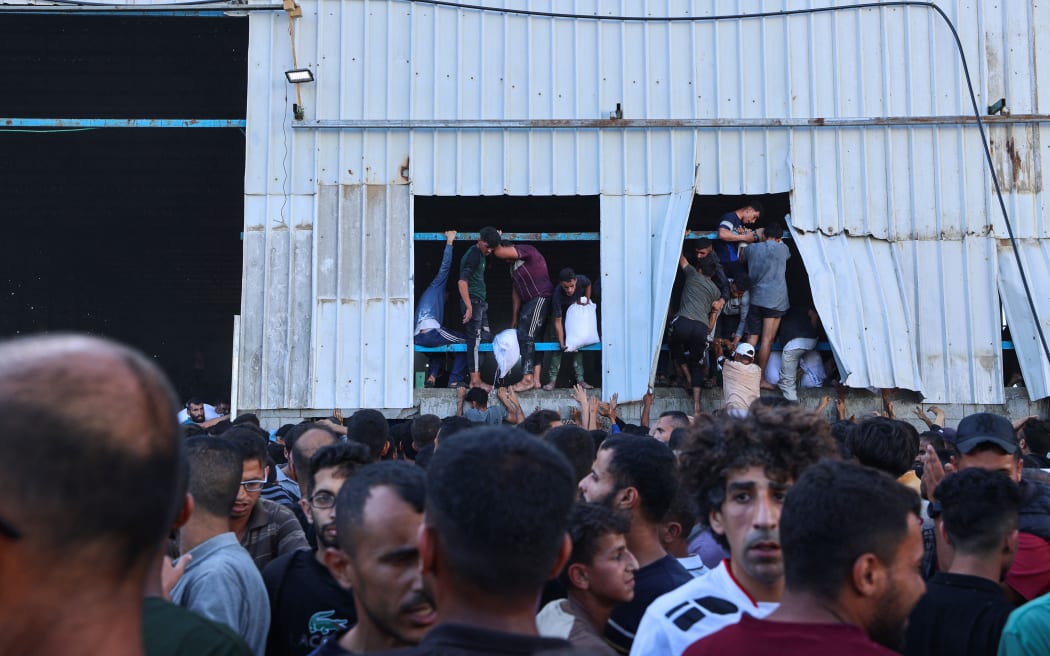 Displaced Palestinians ferry bags of food aid after storming a World Food Programme warehouse in Deir el-Balah in the central Gaza Strip on May 28, 2025. The United Nations on May 28 condemned a US-backed aid system in Gaza following a chaotic food distribution where 47 people were injured, after Israel allowed supplies in at a trickle last week, easing a full blockade imposed on the besieged Palestinian territory for over two months. (Photo by Eyad BABA / AFP)