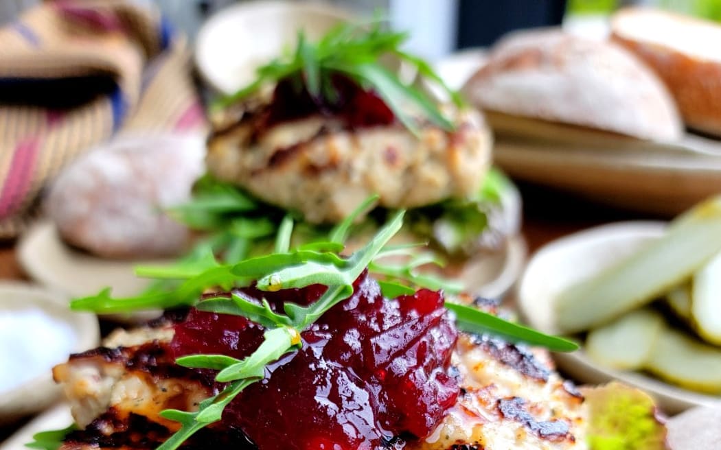 An image of turkey burgers, featuring a turkey mince pattie, topped with cranberry sauce and garnished with rocket leaves.