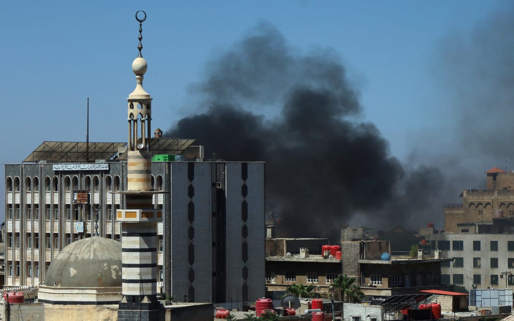 Smoke billows during clashes in the predominantly Druze city of Sweida on July 15, 2025, following clashes between Bedouin tribes and Druze fighters. Syrian government forces entered the majority Druze city of Sweida on July 15, 2025, the interior ministry said, aiming to end clashes with Bedouin tribes that have killed nearly 100 people. (Photo by Shadi AL-DUBAISI / AFP)