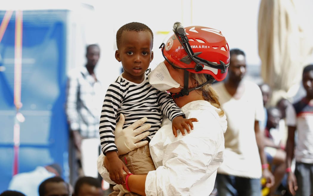 A crew member on the Responder with a young refugee rescued from an overloaded boat on the Mediterranean.