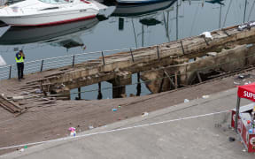 A police investigator inspects the seafront platform in Vigo on August 13, 2018 after a section of a wooden promenade suddenly collapsed.