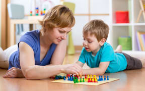 A photo of a mother and son lying on the floor playing a game
