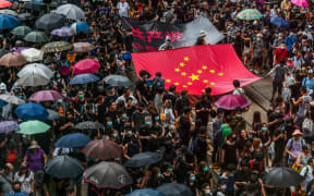 Protesters march with a banner that uses the stars of the Chinese national flag to depict a Nazi Swastika symbol in the Central district of Hong Kong.