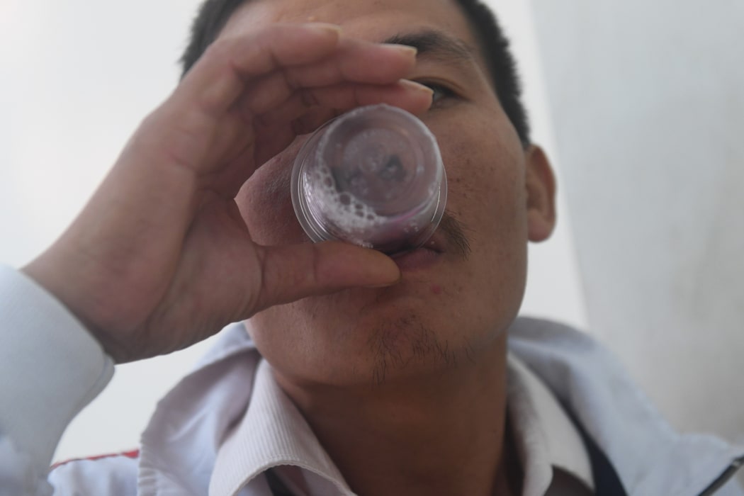 A recovering drug addict taking his daily dose of methadone at a treatment clinic.