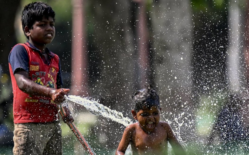 Children play with water during a hot summer day amid severe heatwave in New Delhi on May 31, 2024. Extreme temperatures across India are having their worst impact in the country's teeming megacities, experts said on May 30, warning that the heat is fast becoming a public health crisis. India is enduring a crushing heatwave with temperatures in several cities sizzling well above 45 degrees Celsius (104 degrees Fahrenheit). (Photo by Money SHARMA / AFP)