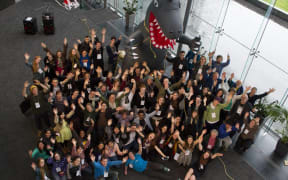 About 100 young people in front of a model of a dinosaur