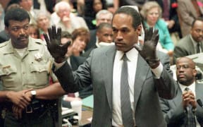 (FILES) O.J. Simpson shows the jury a new pair of Aris extra-large gloves, similar to the gloves found at the Bundy and Rockingham crime scene 21 June 1995, during his double murder trial in Los Angeles, California. Deputy Sheriff Roland Jex(L) and Prosecutor Christopher Darden (R) look on. Simpson has died at the age of 76, his family said on April 11, 2024. (Photo by VINCE BUCCI / POOL / AFP)