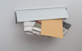 A letter and newspapers in a mail slot