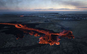 Lava explosions and billowing smoke are seen near residential buildings in the southwestern Icelandic town of Grindavik after a volcanic eruption on January 14, 2024.