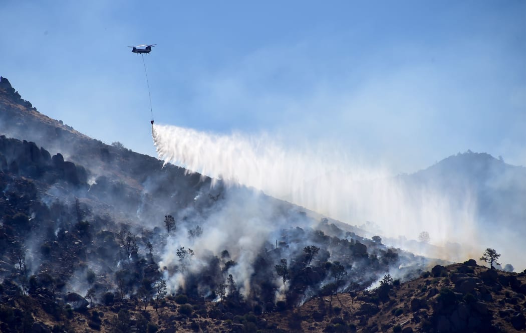 A helicopter drops water over a hillside at Lake Isabella, California on June 24, 2016.