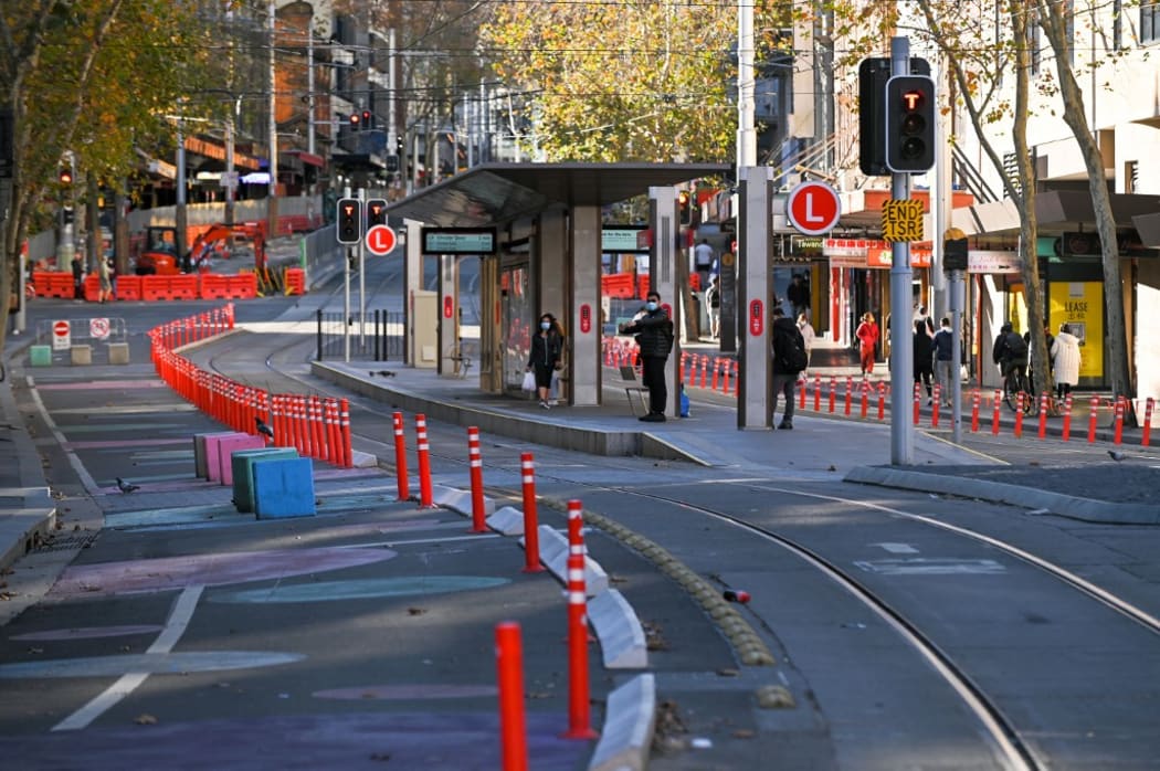 People wait for a tram in the empty central business district in Sydney on June 27, 2021, on the first full day of a two-week Covid-19 coronavirus lockdown.