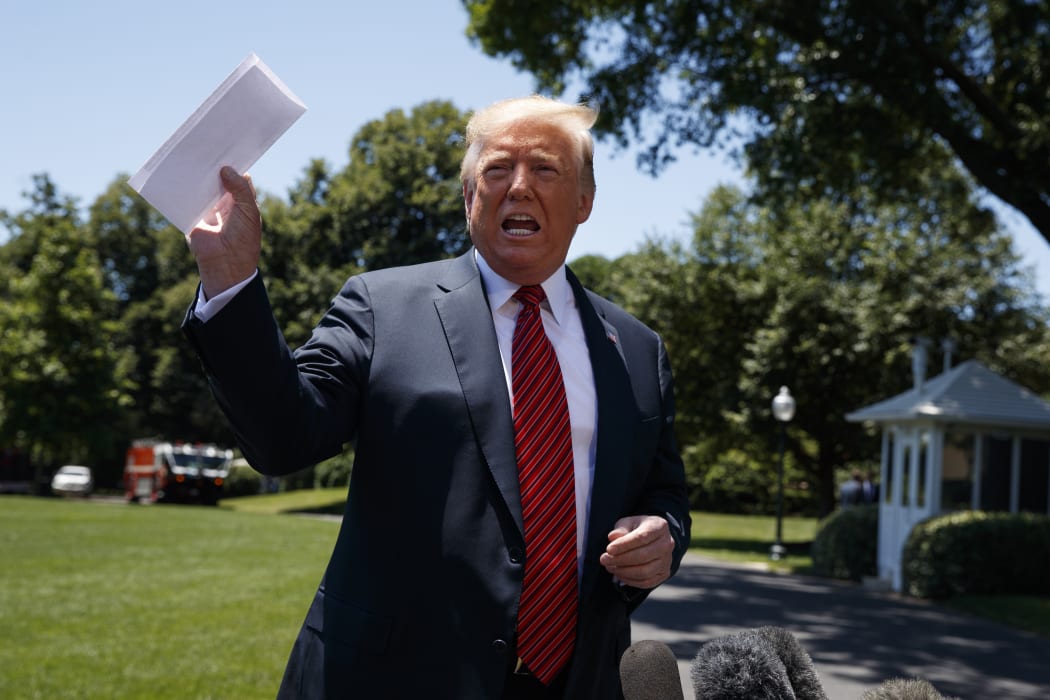 President Donald Trump speaks in Washington to reporters while waving around a paper with details of the US immigration deal with Mexico.