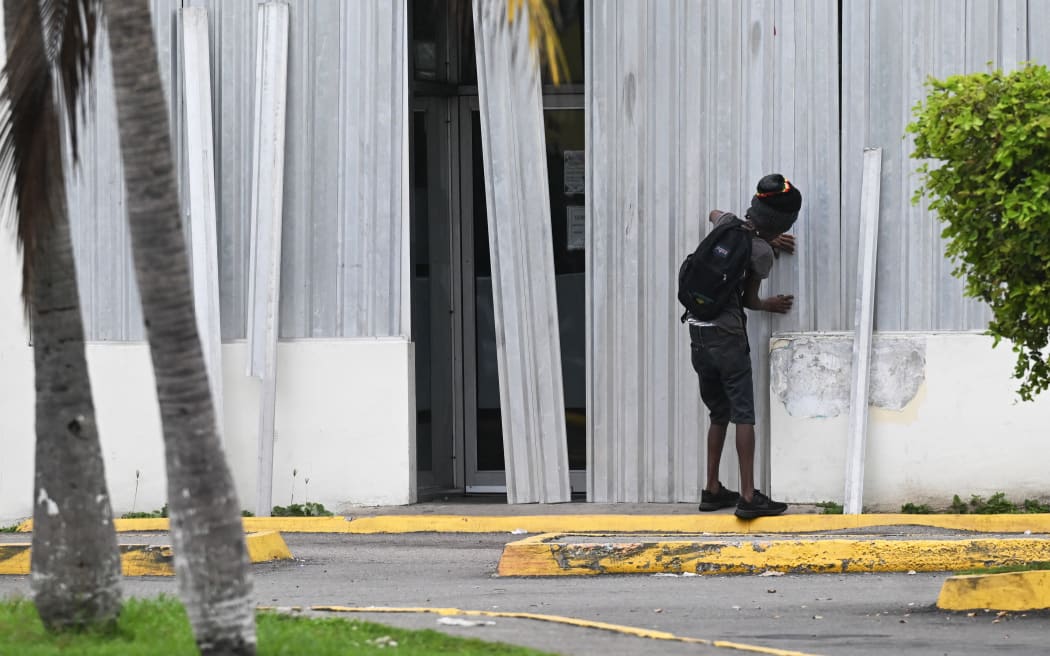 A man installs storm shutters at a business in preparation for the arrival of Hurricane Melissa in Portmore, Jamaica, on 25 October, 2025.