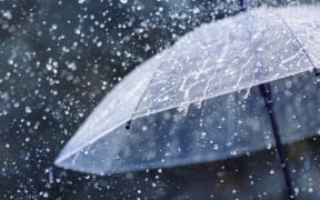 Transparent umbrella under heavy rain against water drops splash background. Rainy weather concept.