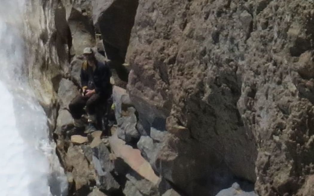 The man near the snowline waiting to be rescued.