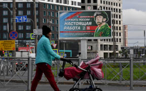 A billboard promoting contract army service with an image of a serviceman and the slogan reading "Serving Russia is a real job" sits in Saint Petersburg on September 20, 2022.