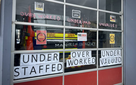The windows of the Auckland city fire station. They are covered in protest slogans: 'UNDER STAFFED - OVER WORKED - UNDER VALUED'.