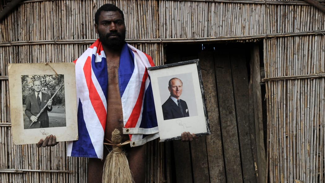 Sikor Natuan, the son of the local chief, holds two official portraits (one holding a pig-killing club) of Britain's Prince Philip in front of the chief's hut in the remote village of Yaohnanen on Tanna.