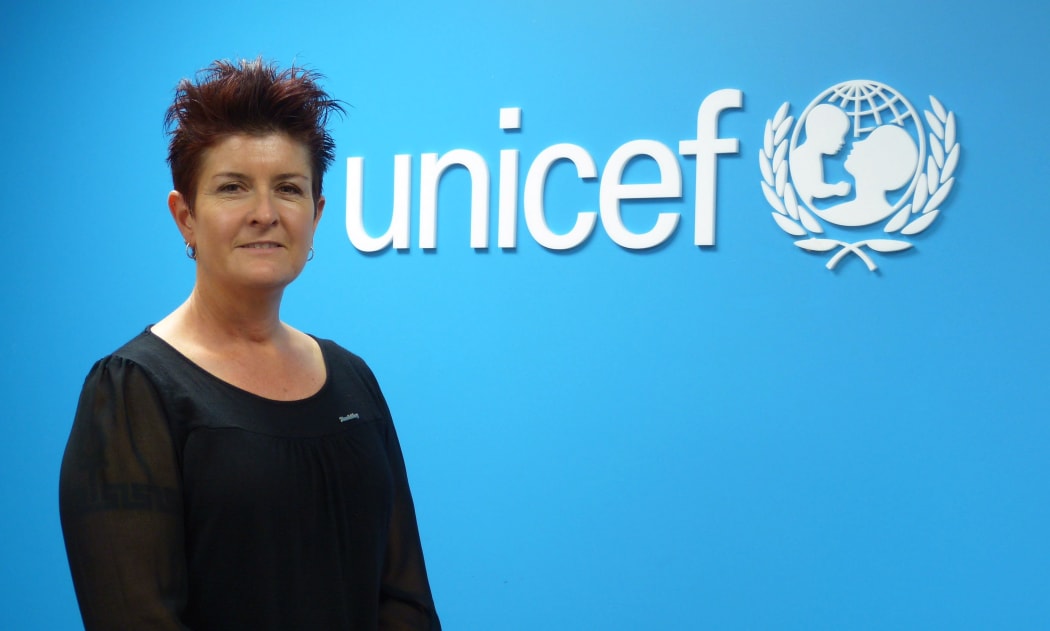 Unicef's Deborah Morris-Travers standing in form of blue wall with Unicef logo