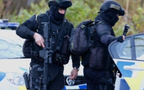 Armed police officers leave an address in Ohakune during the search.