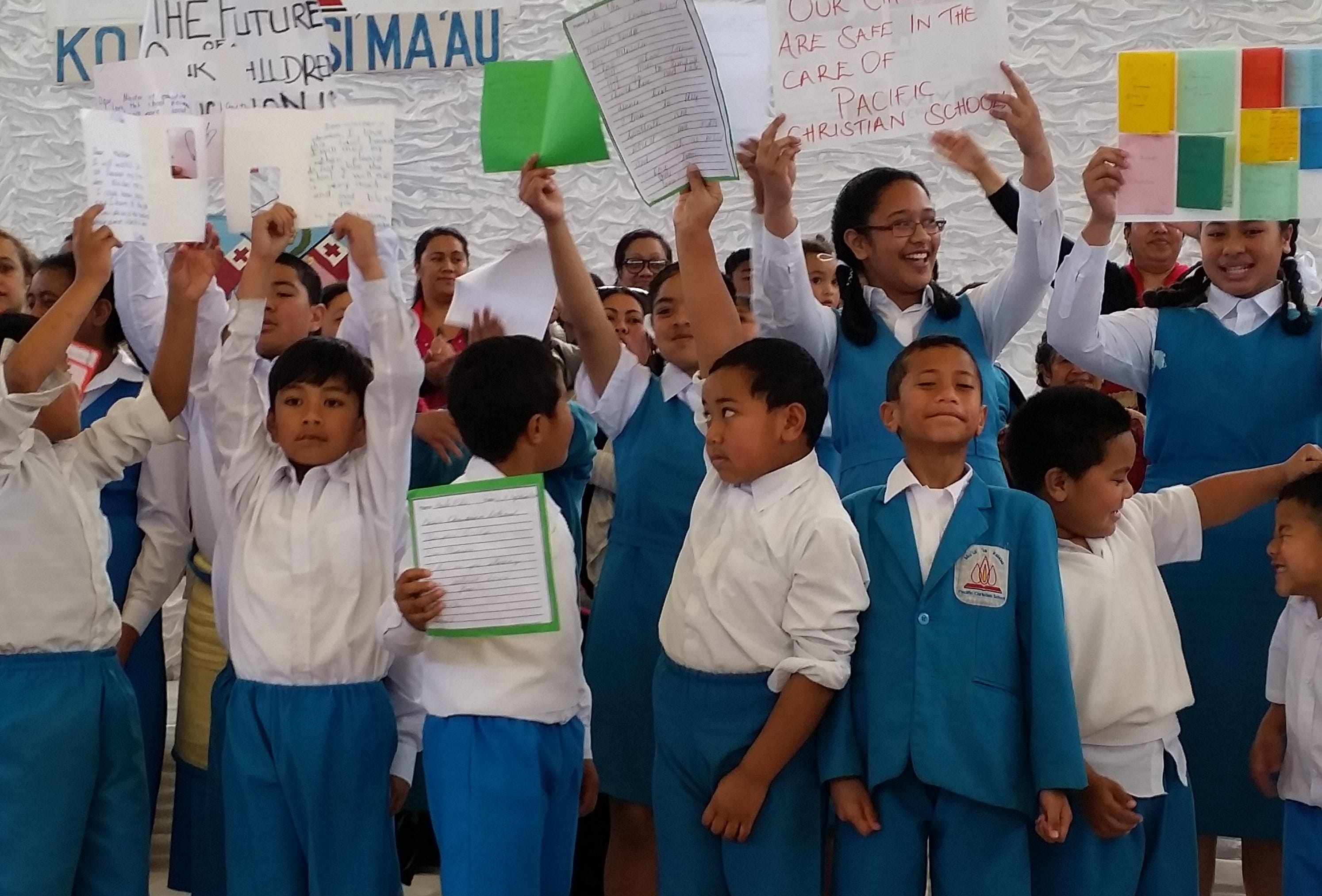 Students and parents hold signs urging the education minister to reverse a suspension of the school's license.