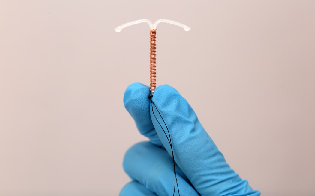 Doctor holding T-shaped intrauterine birth control device.