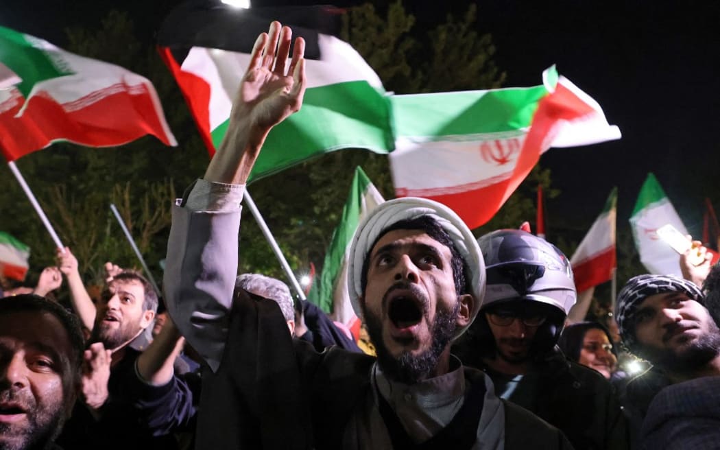 Demonstrators wave Iran's flag and Palestinian flags as they gather in front of the British Embassy in Tehran on April 14, 2024, after Iran launched a drone and missile attack on Israel. Iran's Revolutionary Guards confirmed early April 14, 2024 that a drone and missile attack was under way against Israel in retaliation for a deadly April 1 drone strike on its Damascus consulate. (Photo by ATTA KENARE / AFP)