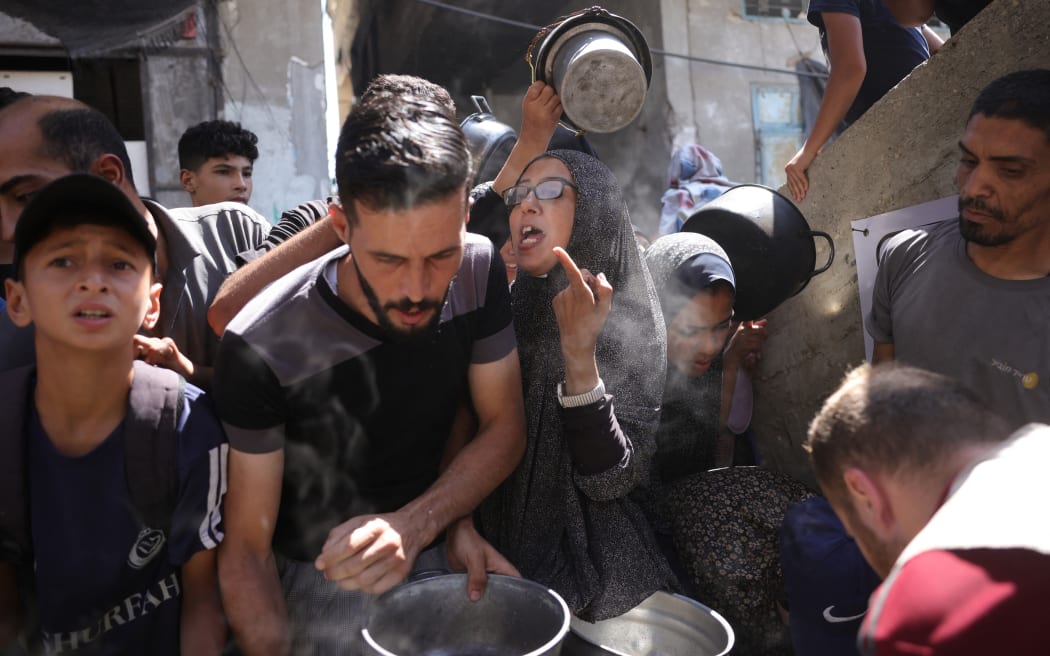 Palestinians line up to receive a hot meal at a food distribution point in Gaza City on 27 June 2025. After more than 20 months of devastating conflict, rights groups say Gaza's population of more than two million face famine-like conditions.