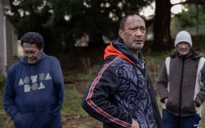 Albie, Rob, and Jason, with traditional face tattoos, stand with their hands in their jumper pockets in front of a tree.