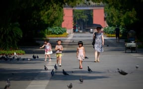 China to allow couples to have three children in major policy shift.
A group of Chinese children prepare to feed pigeons at a park in Beijing on August 7, 2014.