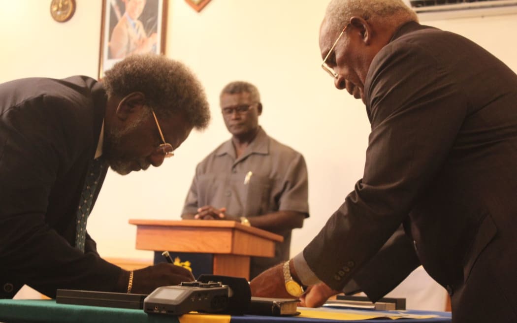 Solomon Islands finance minister Snyder Rini is sworn in by Governor General Sir Frank Kabui as Prime Minister Manasseh Sogavare looks on.