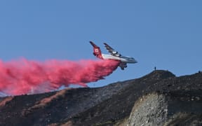 A plane drops flame retardant on a scorched hillside at the Poppy Fire on July 10, 2024 in Santa Clarita, Los Angeles County, California where temperatures reached over 101 degrees Fahrenheit (38 degrees Celsius). A record-breaking heat wave continued to grip the western United States on July 9, smashing records and endangering lives with little relief in sight. 
Approximately 162 million people -- nearly one-half of the US population -- were living in areas under active heat warnings, according to the National Weather Service. (Photo by Robyn Beck / AFP)