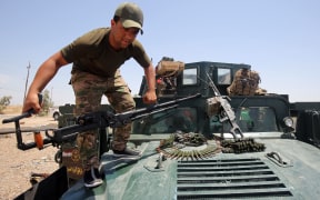 A member of the Iraqi security forces mounts a gun atop a vehicle as they gather on the outskirts of Fallujah as they prepare an operation aimed at retaking the city from the Islamic State (IS) group, on May 22, 2016.