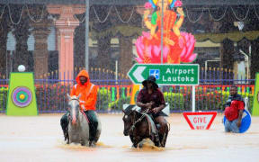 Fiji police officers patrol a flooded Nadi on horseback.