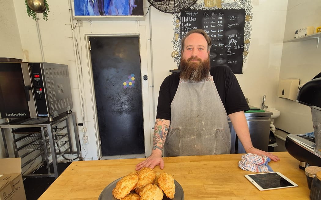 Owner of Onehunga's iTi Cafe, Logan Shilling, serving his freshly baked cheese scones, July 2024.