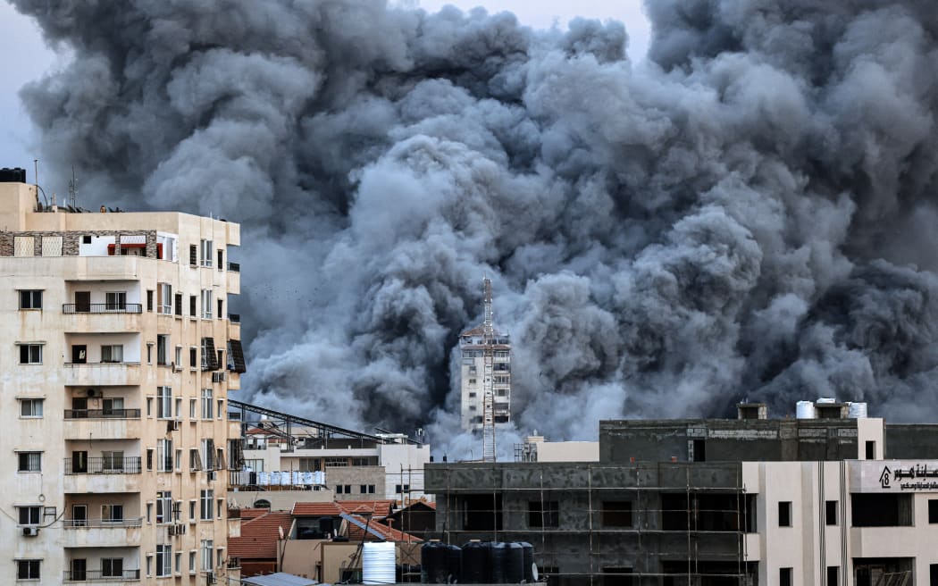 EDITORS NOTE: Graphic content / A plume of smoke rises above buildings in Gaza City on October 7, 2023 during an Israeli air strike that hit the Palestine Tower building. At least 70 people were reported killed in Israel, while Gaza authorities released a death toll of 198 in the bloodiest escalation in the wider conflict since May 2021, with hundreds more wounded on both sides. (Photo by MAHMUD HAMS / AFP)