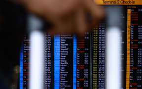 A passenger walks past an electric board showing the status of departing flights at Hong Kong's international airport.