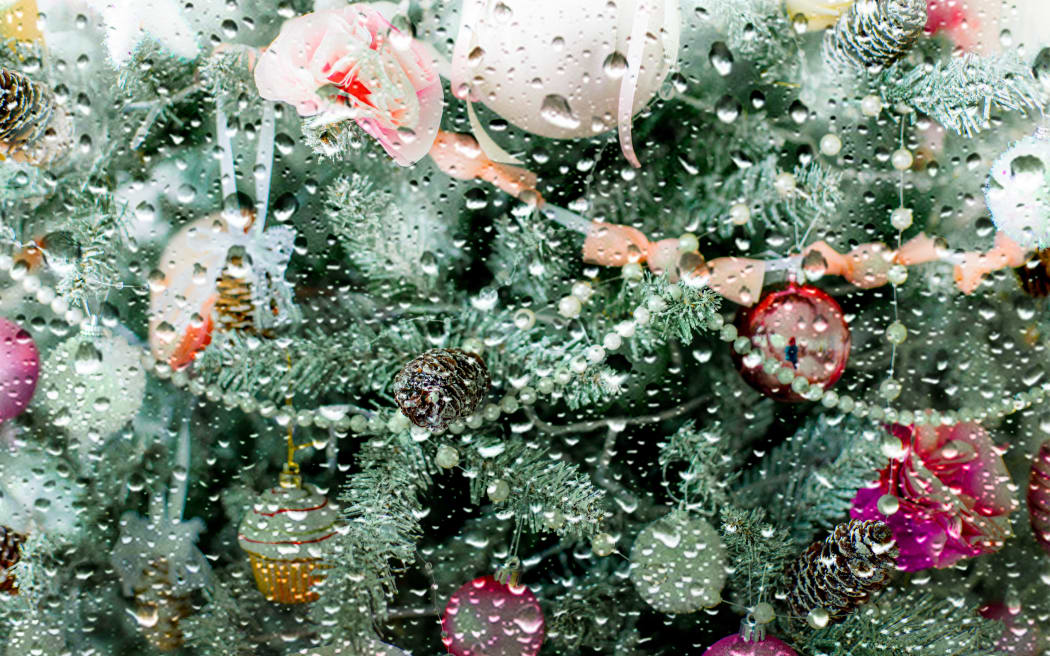 A Christmas tree seen through a window on a rainy day.