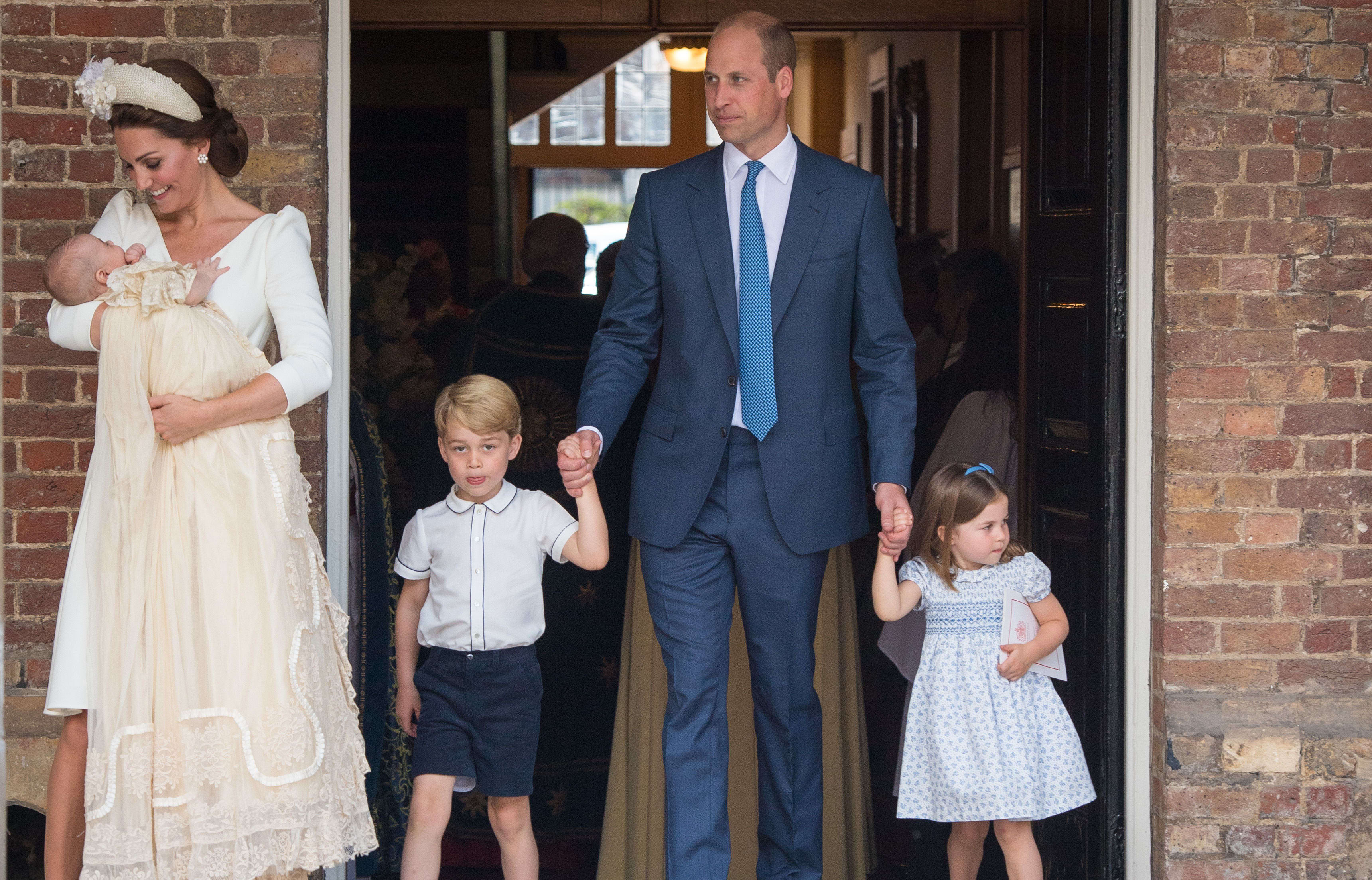 Britain's Princess Charlotte of Cambridge and Britain's Prince George of Cambridge hold hands with their father, Britain's Prince William, Duke of Cambridge, as Britain's Prince Louis of Cambridge is carried by his mother, Britain's Catherine, Duchess of Cambridge.