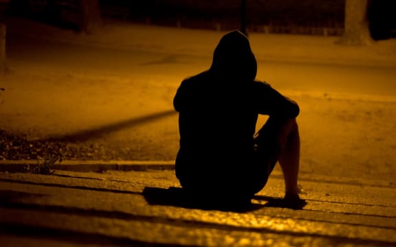 Hooded figure sitting on the road