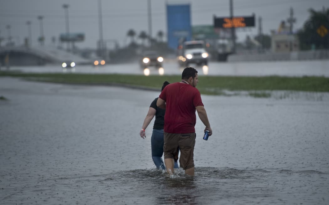 People walk though flooded streets in Houston.