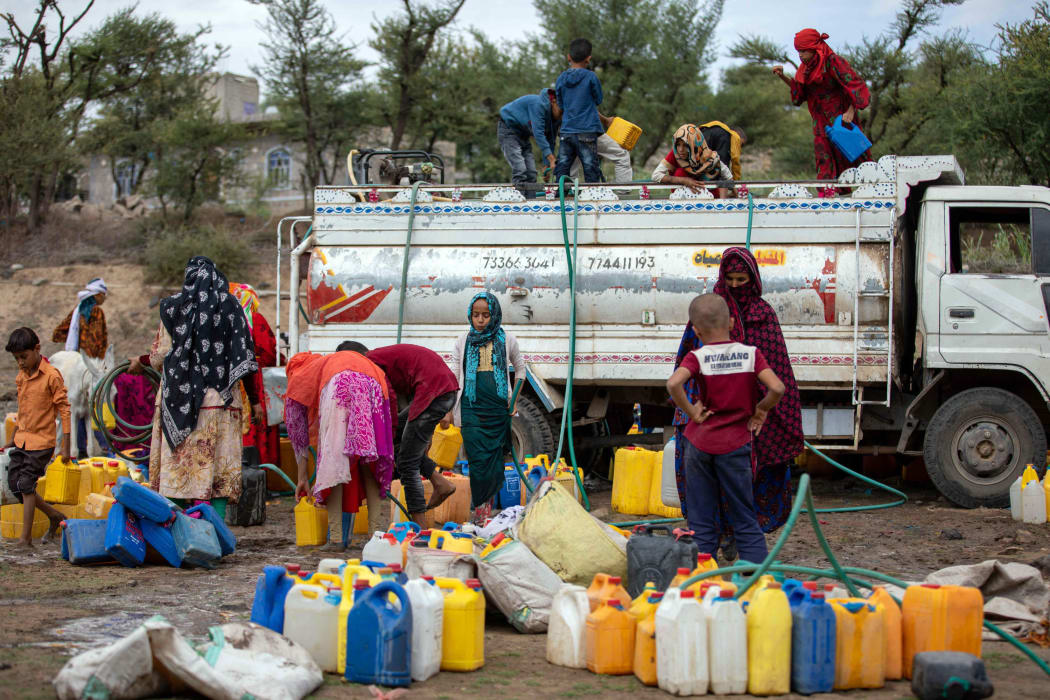 In this file photo taken on August 26, 2021 Yemeni women and children fill their jerricans with water from a tanker in the southwestern Taez Governorate's Al-Maafer district, amidst severe water shortage.