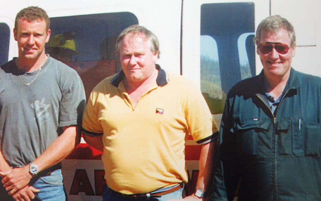 Three men stand alongside each other
