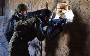 A fighter from the Syrian pro-government forces mans a rifle inside a damaged house during an offensive towards the area of Al-Bab.