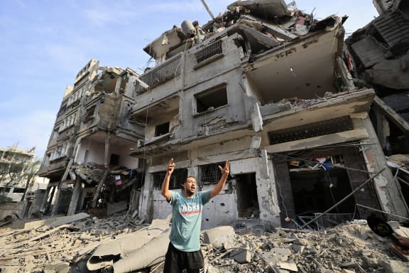 A Palestinian man reacts as he stands amid the destruction in the aftermath of Israeli bombardment in al-Karama district in Gaza City on October 11, 2023. The death toll from five days of ferocious fighting between Hamas and Israel rose sharply overnight as Israel kept up its bombardment of Gaza after recovering the dead from the last communities near the border where Palestinian militants had been holed up. (Photo by Mahmud HAMS / AFP)