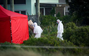 Police forensics taking a bag of evidence back to the tent.