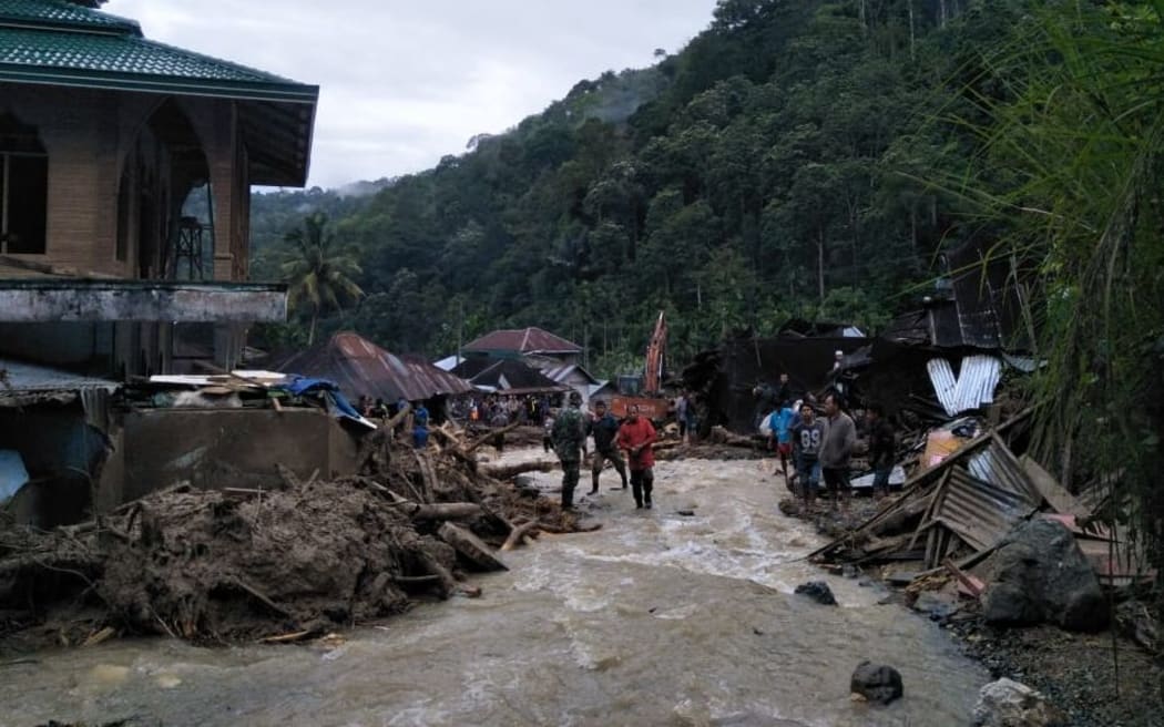 Villagers wade through flood water at the Saladi village in Mandailing Natal, North Sumatra