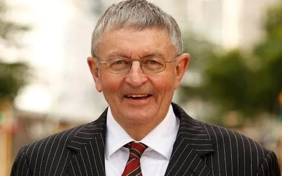 Peter wears a suit and grins at the camera.