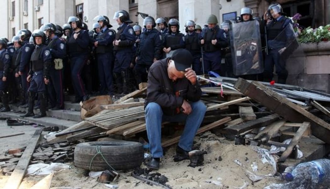 A pro-Russian activist sits in front of policemen guarding the burned trade union building in Odessa.