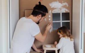 father and daughter painting a playhouse